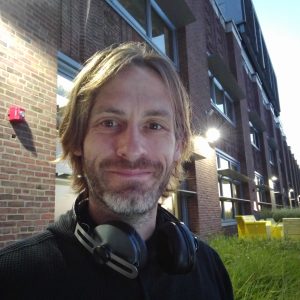 The same portrait of Dirk Primbs outside a brick building, cropped square.